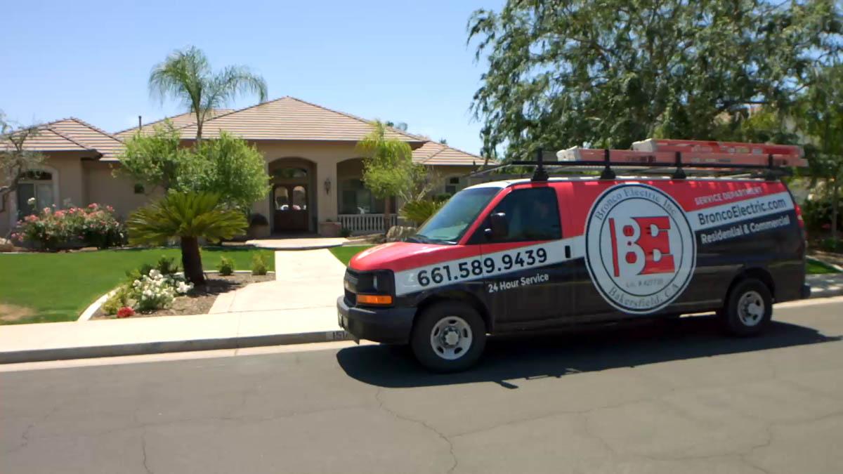 Bronco Electric service van parked in front of a suburban house with landscaped lawn and palm trees