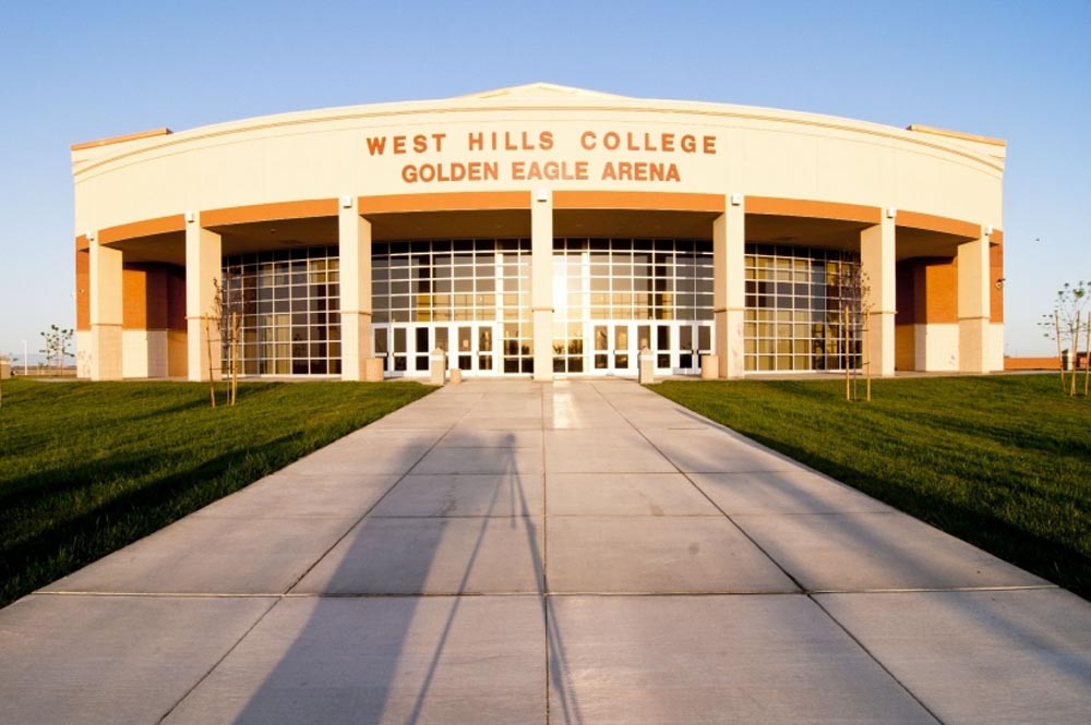West Hills College Golden Eagle Arena facade with glass entrance, central walkway and lawns at sunset.